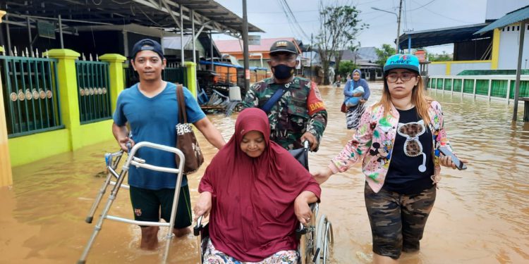 Petugas TNI saat membantu evakuasi warga yang menggunakan kursi roda.