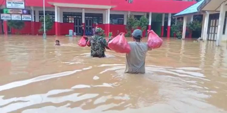 Aparat gabungan saat menyalurkan bantuan logistik ke warga korban banjir yang ada di tempat pengungsian.