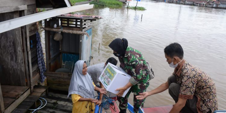 Anggota Kowad Kalsel membagikan paket bantuan kepada warga pesisir sungai yang terdampak banjir.