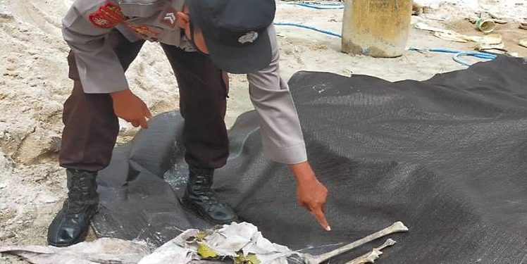 Aparat kepolisian saat mengamankan tulang belulang yang ditemukan di tumpukan pasir campuran semen.