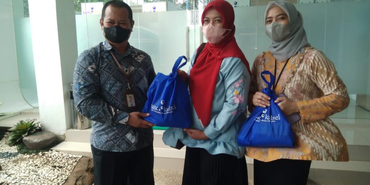 Kepala Divisi Sekretaris Perusahaan Suriadi saat menyerahkan secara simbolis bantuan sembako gratis kepada Bendahara FWE Kalsel Raudah Annisa. (foto : Bank Kalsel)