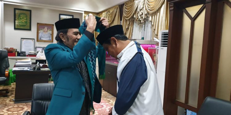 H Rhoma Irama menyematkan syal Fahmi Tamami kepada Gubernur Kalimantan Selatan H Sahbirin Noor. (Foto : Humas Pemprov Kalsel)