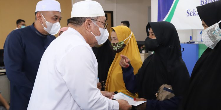 Plt Bupati HSU Husairi Abdi saat menyerahkan uang zakat Bank Kalsel kepada penerima. (Foto : Bank Kalsel)