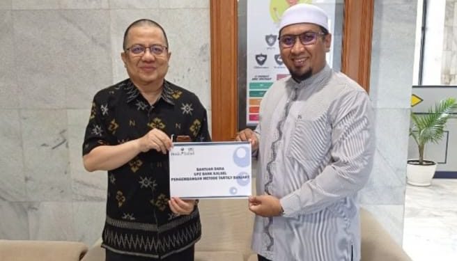 Penyerahan bantuan dana untuk pengembangan Metode Tatily Banjary dilakukan secara simbolis oleh Direktur UPZ Bank Kalsel HM Fajri Muhtadi kepada Direktur Manajemen Pendidikan Qur'an Metode Tartily Banjary, Ustadz Fakhrie Hanif. (foto : Humas Bank Kalsel)