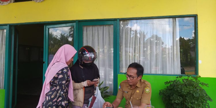 Orangtua murid saat bertanya Mengenai cara pendaftaran PPDB online di Posko layanan yang disiapkan pihak sekolah. (foto : shn)