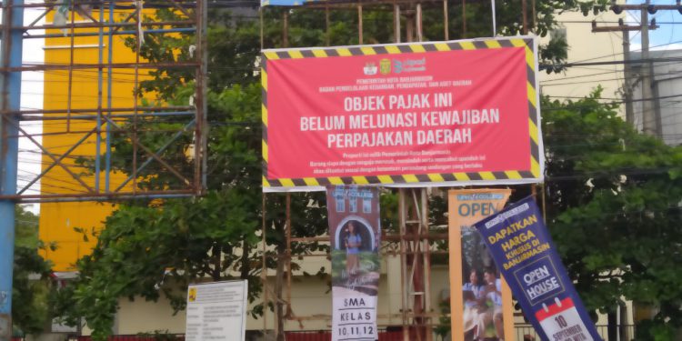 Papan reklame yang dipasangi spanduk menunggak pajak. (foto : shn)