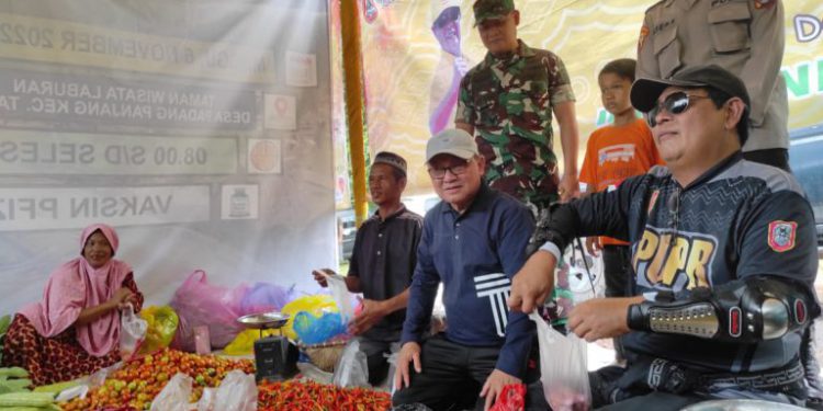 Gubernur Kalsel H Sahbirin Noor didampingi Bupati Tabalong H Anang Syakhfiani duduk bak pedagang kemudian 'jualan sayur' melayani masyarakat yang ingin mendapatkan sayuran gratis di Pasar Rakyat. (foto : istimewa)