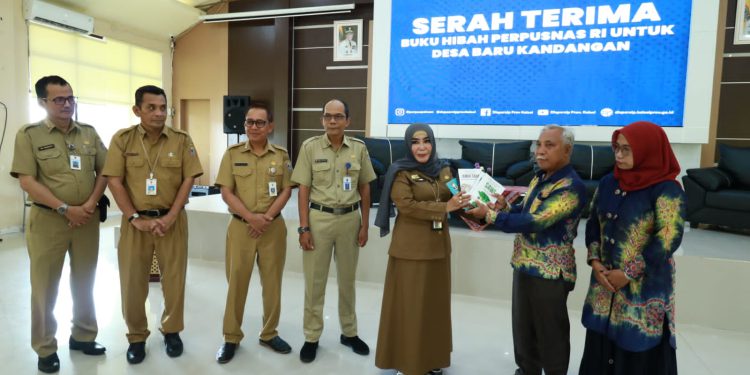 Kepala Dispersip Kalsel Hj Nurliani Dardie menyerahkan buku hibah Perpusnas RI untuk Desa Baru. (foto : istimewa/Dispersip Kalsel)