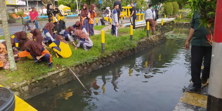 Pihak kelurahan dan petugas kebersihan Sungai Miai bersama pelajar SMKN 2 Banjarmasin saat membersihkan sungai depan sekolah. (foto : shn)