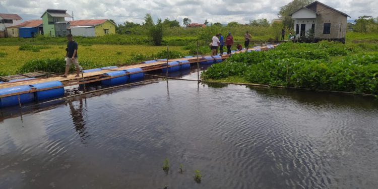 Keluarga Zainal dan warga saat mencoba titian apung sementara untuk akses jalan menuju rumah Zainal. (foto : shn)