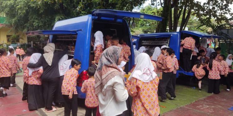 Para pelajar SDN 1 Komet Banjarmasin saat antre untuk mendapatkan buku bacaan dari Mobil Pusling Palnam yang berkunjung ke sekolah tersebut. (foto : istimewa/Dispersip Kalsel)