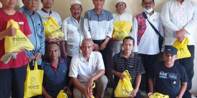 Warga berfoto bersama usai mendapat bantuan paket sembako YN'S Center.