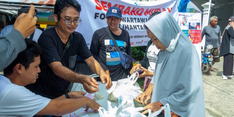 Ian Jurnal, salah satu anggota FWE Kalsel saat melayani pembeli di kegiatan sembako murah. (foto : istimewa)