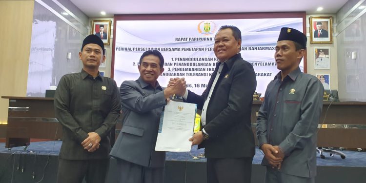 Wakil Walikota Banjarmasin Arifin Noor jabat tangan Wakil Ketua DPRD Banjarmasin Matnor Ali sambil menunjukan dokumen empat Perda yang disahkan. (foto : smr/seputaran)