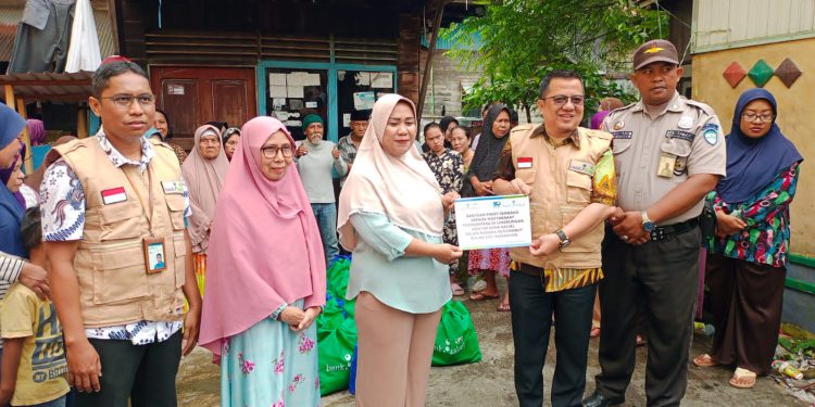 Direktur UPZ Bank Kalsel Fajri Muhtadi secara simbolis menyerahkan bantuan paket sembako kepada perwakilan warga. (foto : istimewa/Bank Kalsel)