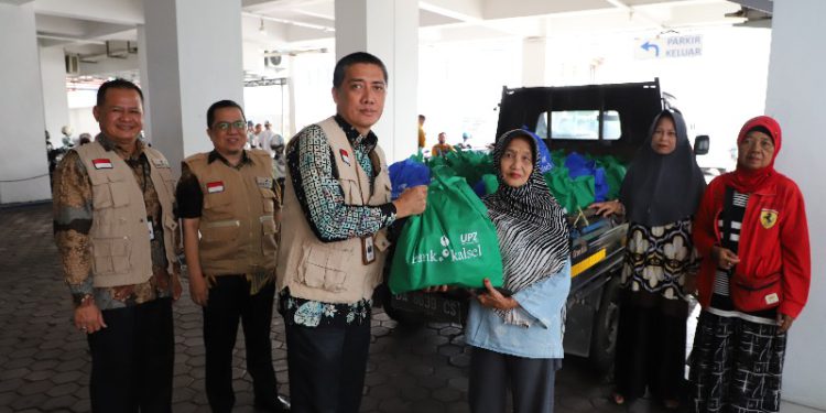 Plt Dirut Bank Kalsel Fachrudin saat menyerahkan bantuan paket sembako kepada perwakilan warga. (foto : istimewa/Bank Kalsel)