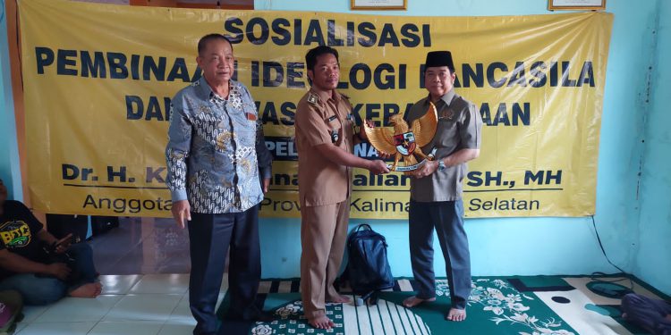 Anggota DPRD Kalsel, Dr.H.Karli Hanafi Kalinada memberikan cendera mata berupa Lambang Negara Garuda Pancasila yang diterima Kepala Desa Sungai Pantai Fauzi. (foto : istimewa)