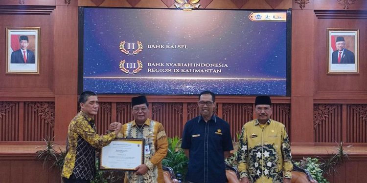 Gubernur Kalsel H Sahbirin Noor menyerahkan penghargaan terbaik penyelenggaraan KUR yang diterima Dirut Bank Kalsel Fachrudin. (foto : istimewa)