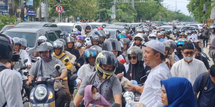 Pembagian nasi bungkus gratis oleh Pemko Banjarmasin kepada jemaah Haul Guru Sekumpul yang melintas di Jalan A Yani Km 6, Banjarmasin. (foto : shn/seputaran)