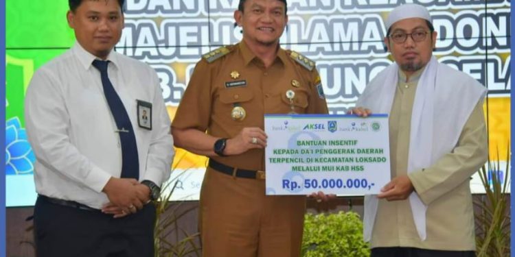 Pj Bupati HSS Hermansyah saat penyerahan bantuan instensif Dai dari Bank Kalsel.(FOTO:IST)