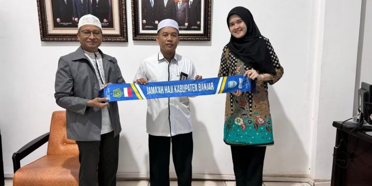 Secara Simbolis penyerahan syal oleh Kepala Bank Kalsel Syariah Cabang Martapura Angga Ginanjar Prasetya kepada Ketua Kloter BDJ 1 Akhmad Nisfuwani.(FOTO:IST)