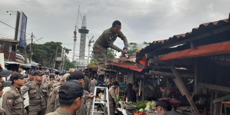 Petugas Satpol PP Banjarmasin saat memotong atap lapak pedagang di Jalan Pasar Lama Laut. (foto : shn/seputaran)