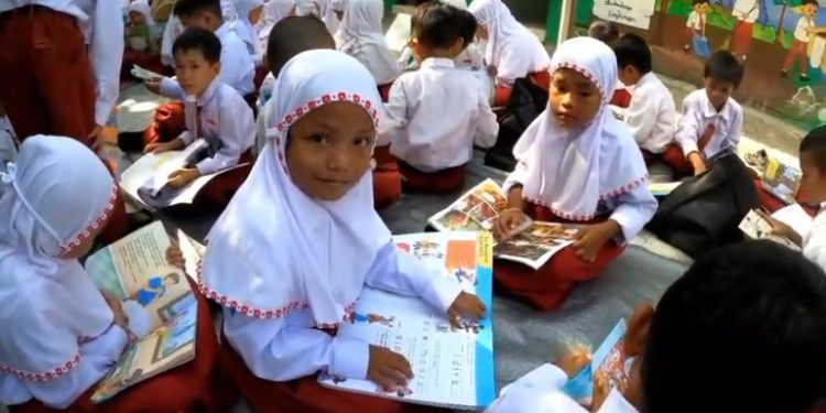 Murid SD Negeri Pekapuran Raya 5 tampak antusias saat membaca buku koleksi Perpus Palnam yang datang dengan trail. (foto : istimewa)