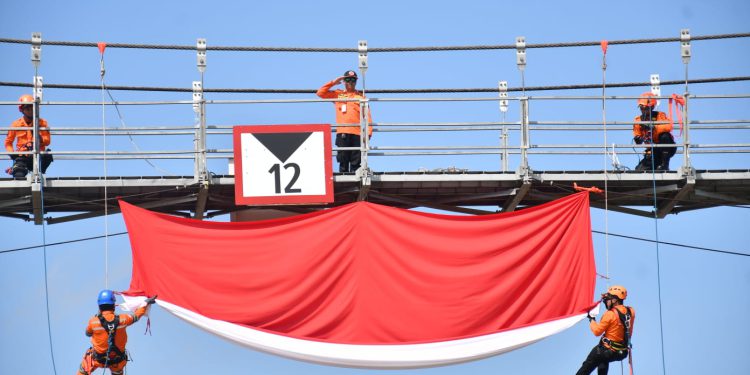 Petugas BPBD Banjarmasin saat kibarkan Bendera Merah Putih di jembatan Bromo. (foto : shn/seputaran)