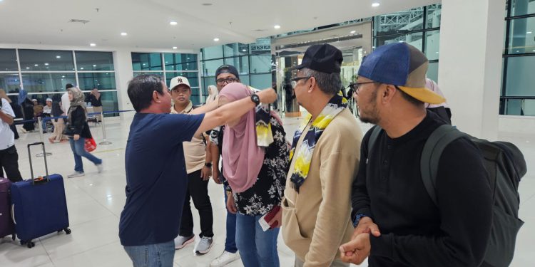 Ketua PWI Kalsel Zainal Helmie menyambut kedatangan enam delegasi wartawan Malaysia dengan mengalungkan slempang dan topi HPN 2025. (foto : istimewa)