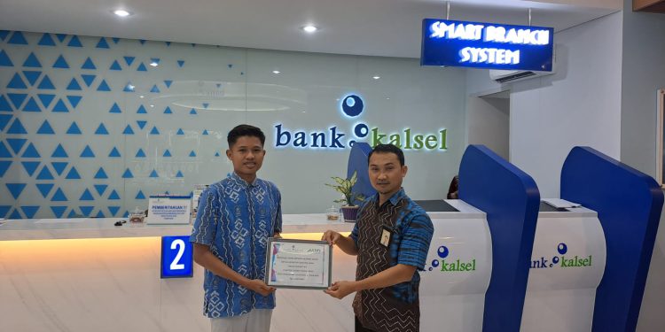 Kepala Bank Kalsel Cabang Barabai, Muhaini Achyar saat menyerahkan bantuan kepada Akhmad Fauzi. (foto : Bank Kalsel)