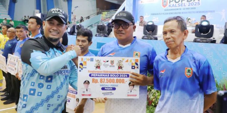 Plt Kepala Dispora Kalsel Muhammad Fitri Hernadi saat menyerahkan bonus kepada salah satu atlet. (foto : Adpim Kalsel)