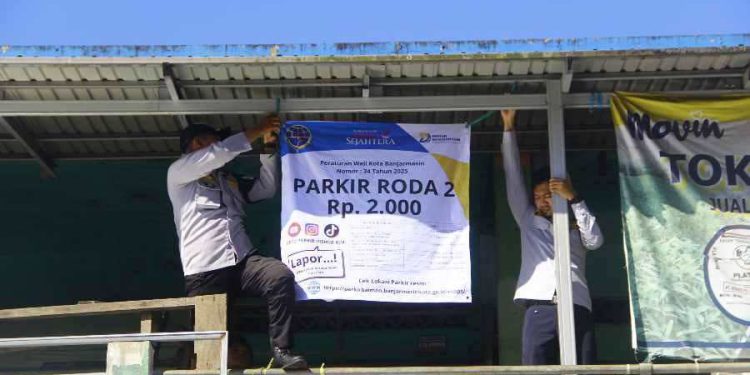 Personel Dishub Banjarmasin memasang spanduk tarif baru parkir di kawasan Pasar Baru. (foto : shn/seputaran)