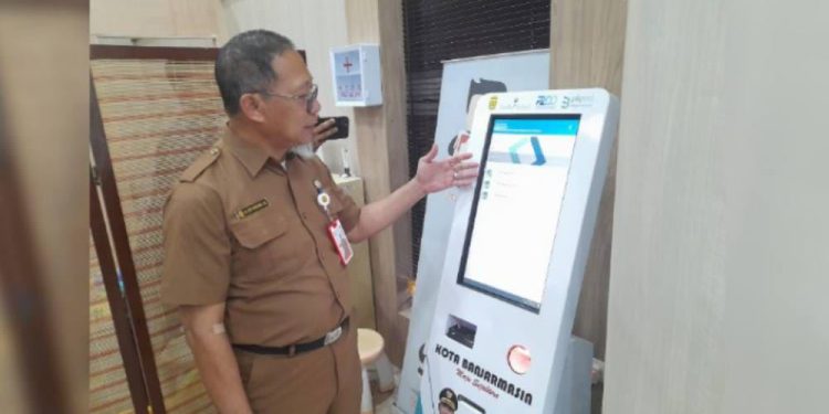 Kepala BPKAD Banjarmasin Eddy Wibowo saat mencoba alat M-Kios untuk pembayaran pajak bagi WP. (foto : shn/seputaran)