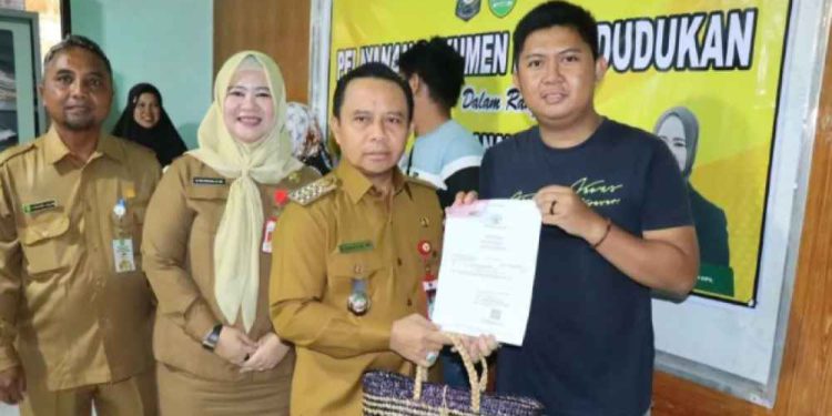 Bupati Tapin H Yamani menyerahkan secara simbolis dukumen kependudukan pada pelayanan adminduk penangan stunting, di Puskesmas Tambarangan. (foto : Prokopim Pemkab Tapin)