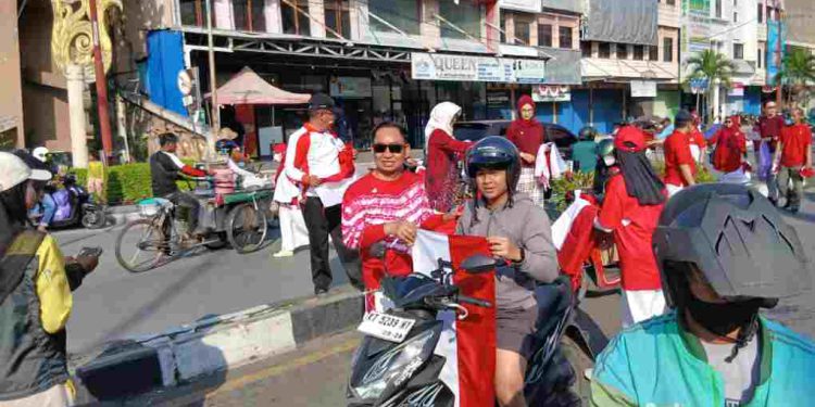 Kepala DPMPTSP Kota Banjarmasin Ari Yani bersama jajarannya membagikan bendera Merah Putih kepada pengendara yang melintas. (foto : shn/seputaran)
