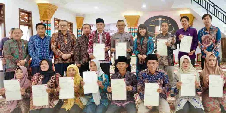 Warga foto bersama sambil menunjukan dokumen Hak Adat yang didaftarkan lewat Tanah Ulayat. (foto : Biro Humas ATR/BPN)