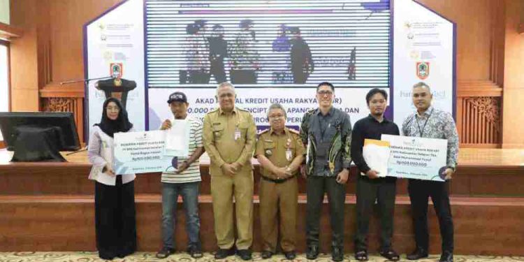 Dirut Bank Kalsel Fachrudin foto bersama dengan dua penerima KUR saat kegiatan akad massal KUR. (foto : Bank Kalsel)
