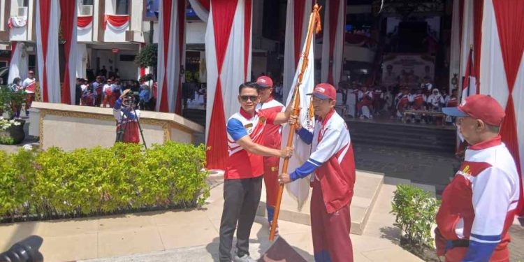 Walikota Banjarmasin HM Yamin serahkan bendera ke Ketua KONI Banjarmasin Hermansyah tanda dilepasnya para atlet Banjarmasin untuk ajang Porprov di Tanah Laut. (foto : shn/seputaran)