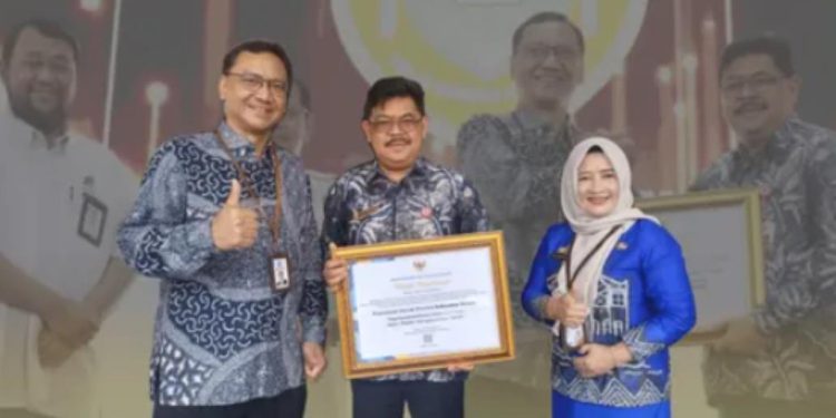 Plt Asisten Pemerintahan dan Kesejahteraan Rakyat Setdaprov Kalsel, Muhamad Muslim sambil memegang Penghargaan Kalsel terbaik penyelenggaraan kearsipan berfoto bersama dengan Kepala Dispersip Kalsel Sri Mawarni. (foto : IG Perpuspalnam)