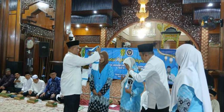 Sekdakot Banjarmasin Dolly Syahbana saat pasangkan syal kepada perwakilan CJH asal Banjarmasin, sebagai tanda dilepasnya CJH berangkat ke Tanah Suci. (foto : shn/seputaran)