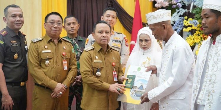 Bupati Tapin, H Yamani didampingi Wabup H Juanda menyerahkan secara simbolis buku nikah kepada peserta Isbat Nikah. (foto : istimewa)