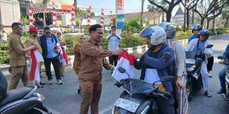 Plt Kabag Umum Setdako Banjarmasin Ahmad Zazuli saat membagikan Bendera Merah Putih ke pengendara. (foto : shn/seputaran)
