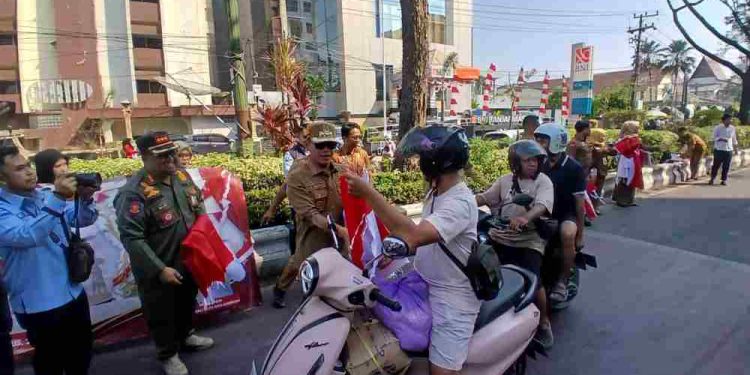 Walikota Banjarmasin HM Yamin saat membagikan Bendera Merah Putih kepada pengendara yang melintas. (foto : shn/seputaran)
