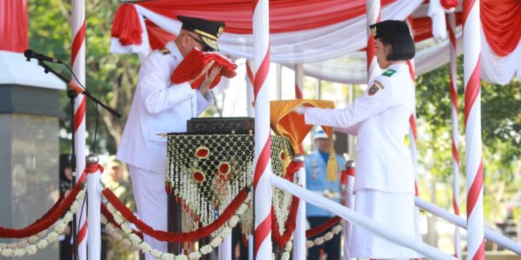 Gubernur Kalsel H Muhudin cium bendera Merah Putih sebelum menyerahkan kepada anggota Paskibraka pada upacara peringatan HUT ke-81 Kemerdekaan RI. (foto : adpim kalsel)