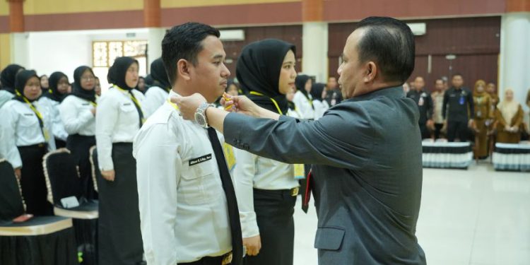 Bupati Tapin H Yamani saat memasangkan ID Card kepada perwakilan PPPK yang mengikuti orientasi. (foto : istimewa)