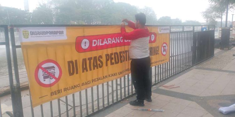 Petugas saat memasang spanduk larangan berjualan di sepanjang jalur pedestrian Siring Menara Pandang. (foto : shn/seputaran)
